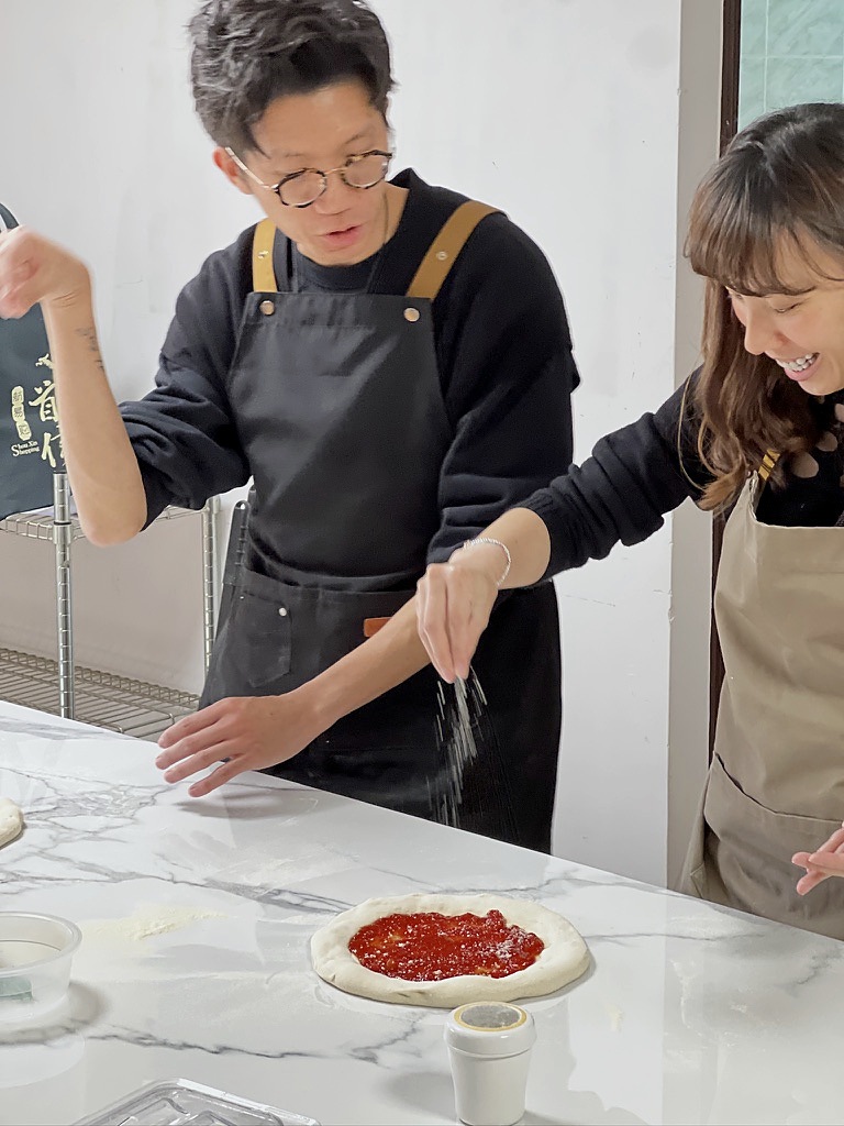 參加者一同為 Pizza 加上配料